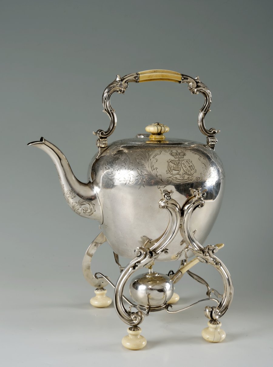 A SILVER KETTLE WITH A WARMER