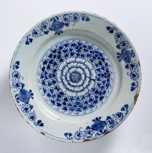 A GROUP OF TWO FAÏENCE PLATES WITH A ROSETTE AND EVERLASTING FLOWERS