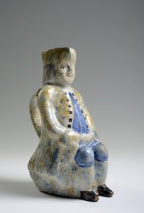 A FAÏENCE PITCHER IN THE FORM OF A SEATED MALE FIGURE