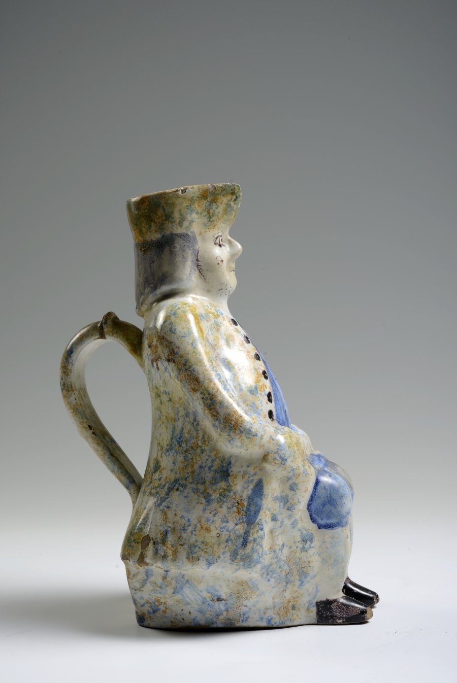 A FAÏENCE PITCHER IN THE FORM OF A SEATED MALE FIGURE