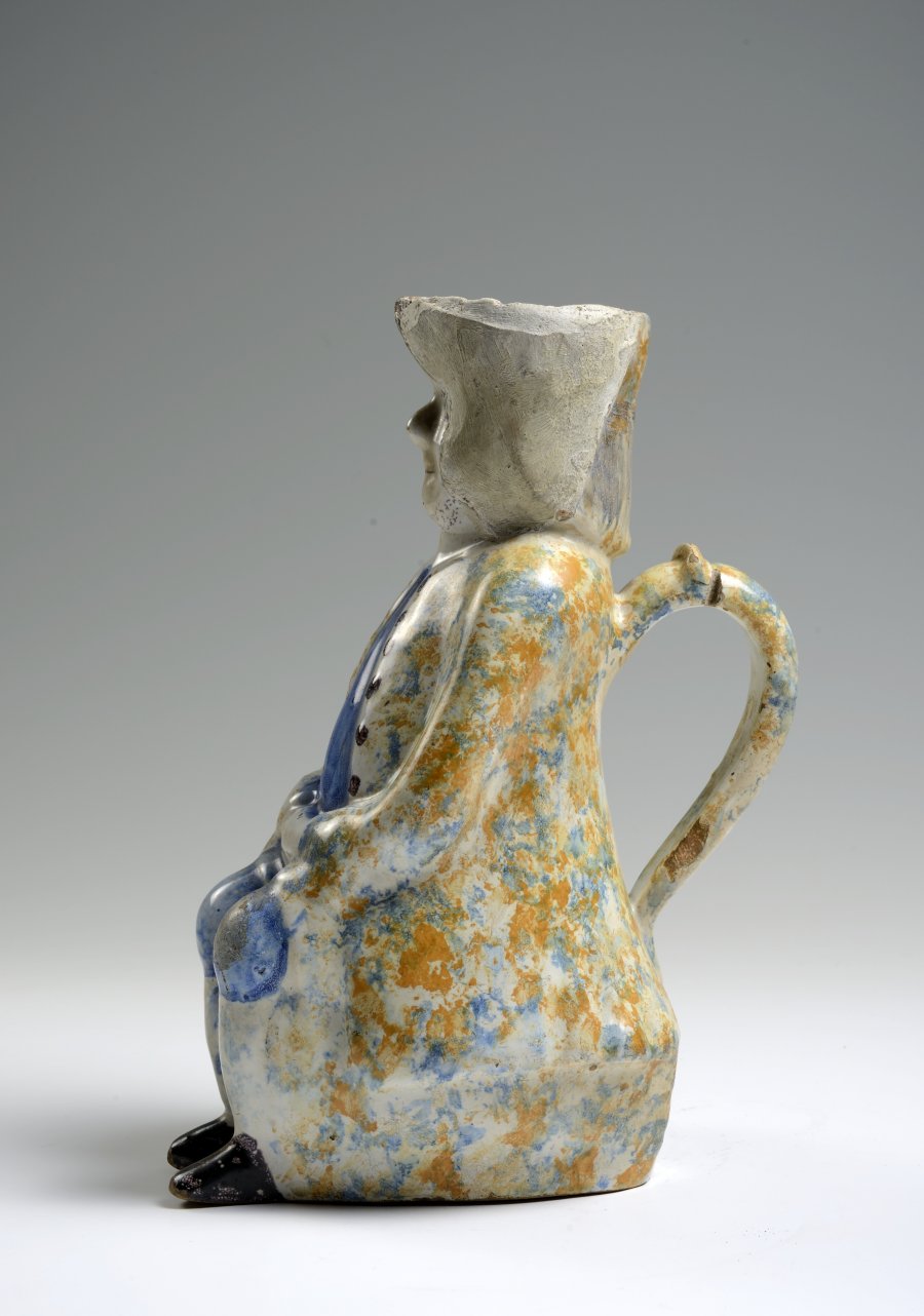 A FAÏENCE PITCHER IN THE FORM OF A SEATED MALE FIGURE