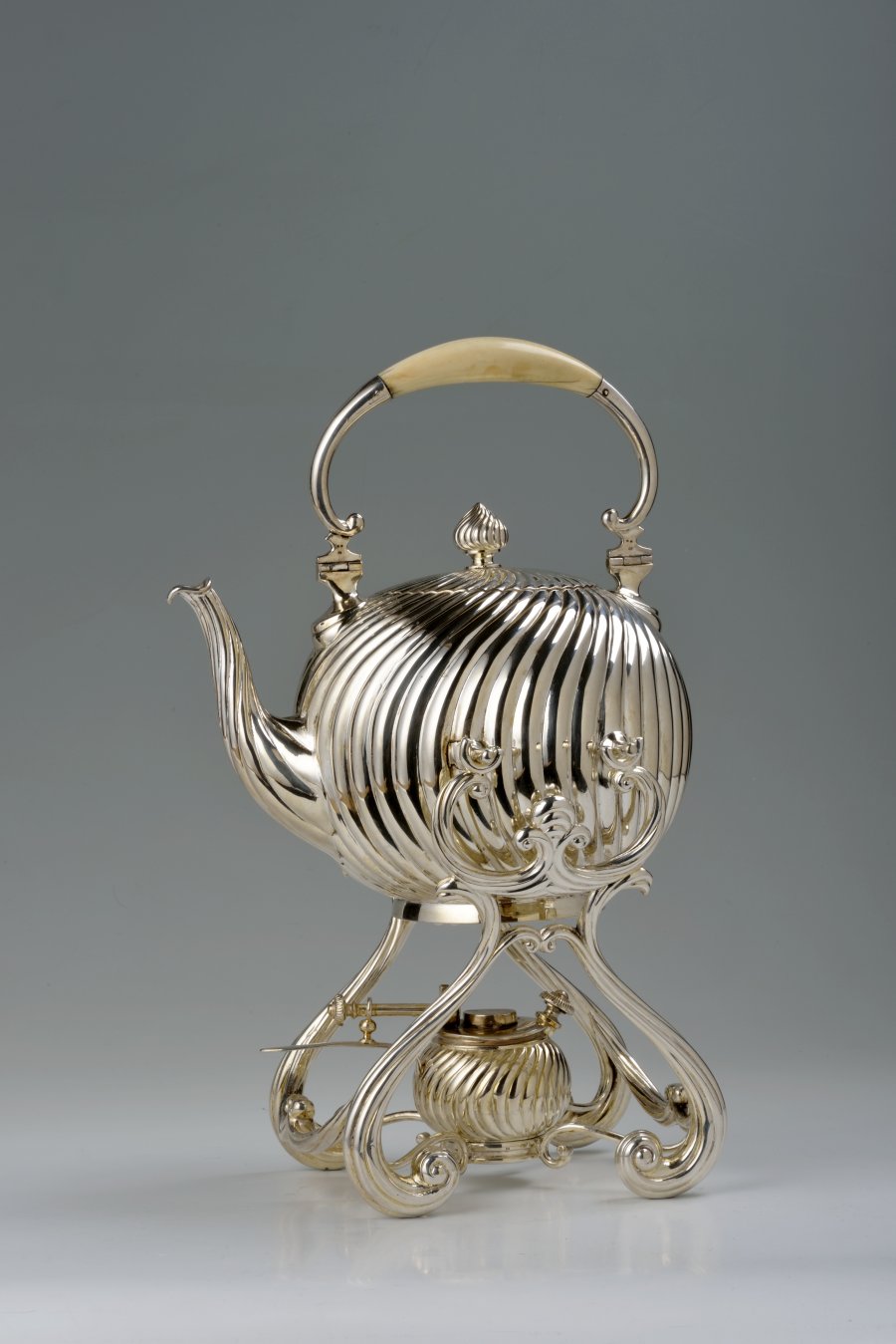 A SILVER KETTLE WITH A WARMER