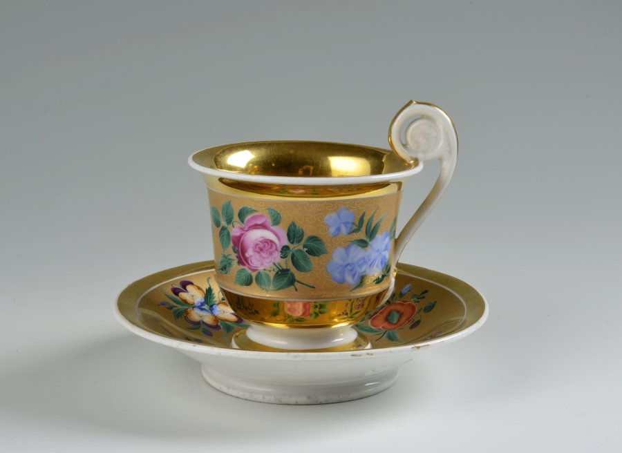 A CUP AND SAUCER WITH A FLORAL DECORATION